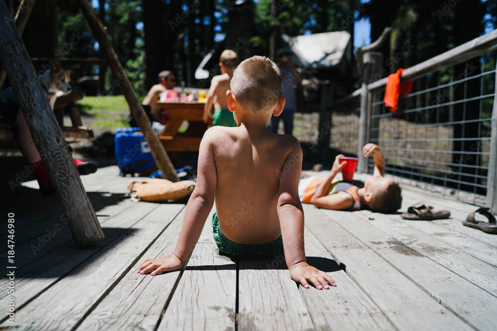 Rear view of boy sitting on a wooden floor during summer