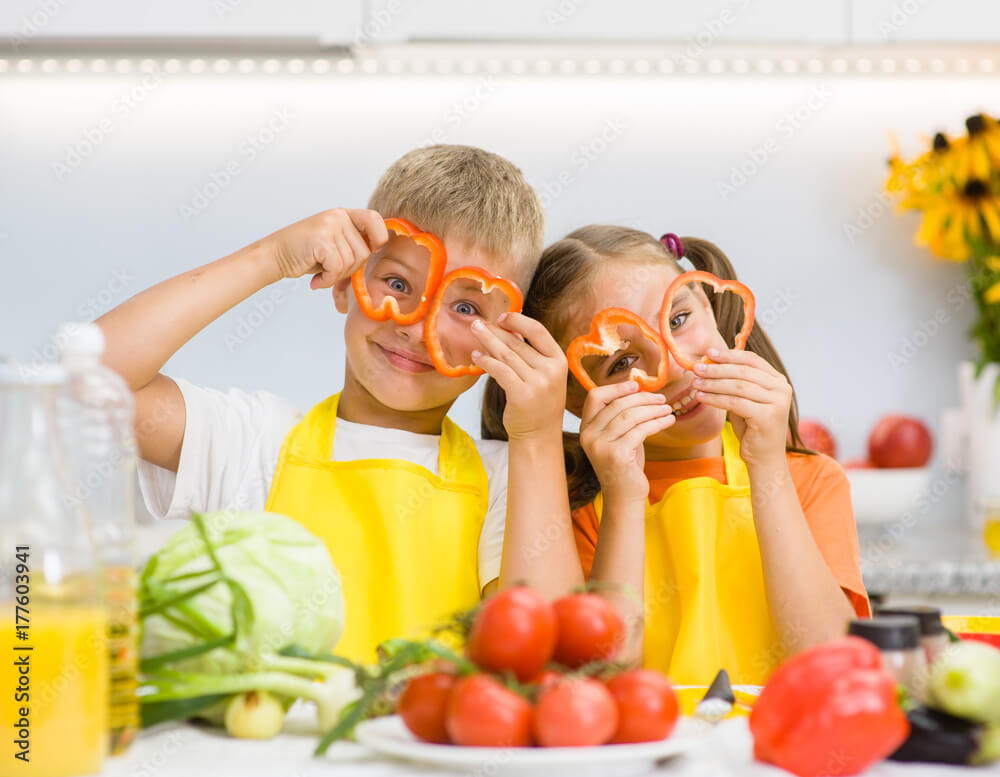 The Link Between Eczema and Food Allergies in Children: What You Need to Know 4 Happy kids having fun with food vegetables at kitchen holds pepper before his eyes like in glasses