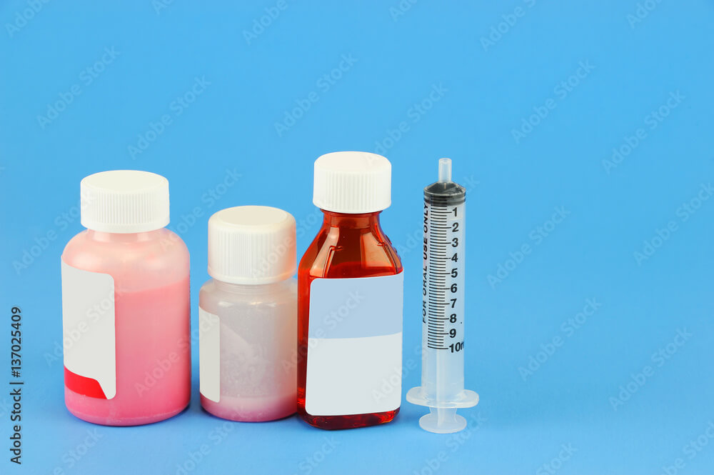 Prescription medicine bottle and oral syringe for baby isolated on blue background
