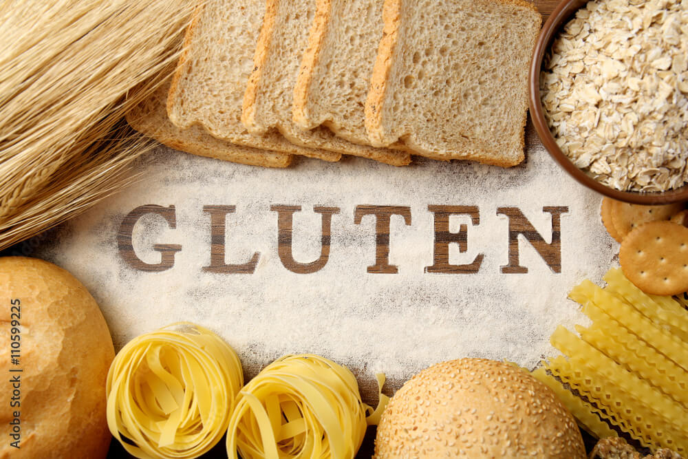 The word GLUTEN and flour products on wooden surface closeup